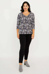 Model standing, front view in Mia Top Black Feather, black pants, and grey shoes