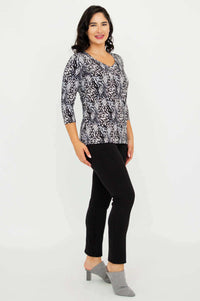 Side angle view of model wearing Mia Top Black Feather, black pants, and heels