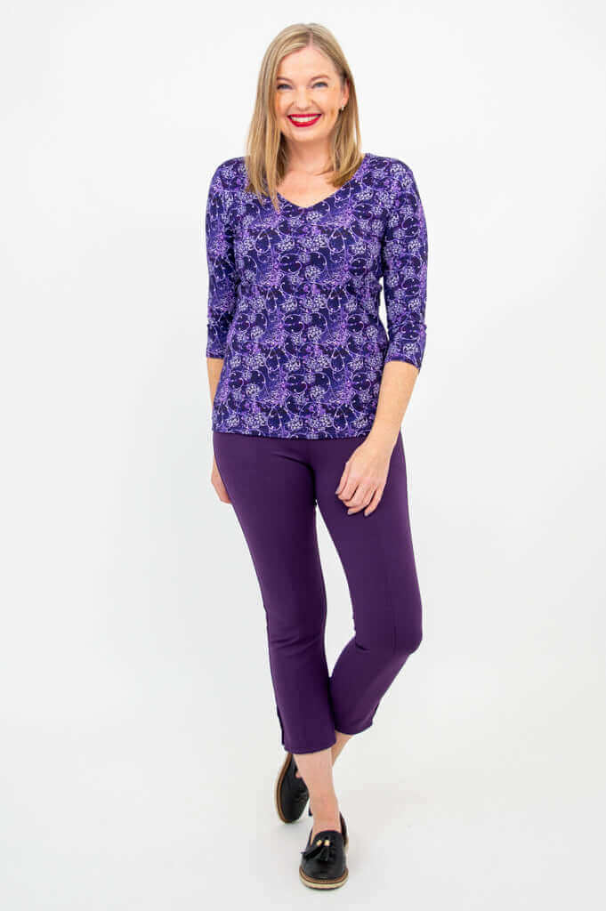 Woman standing front-facing in Mia Top with violet trellis pattern and purple cropped pants