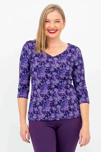 Front view of woman wearing violet patterned Mia Top with 3/4 sleeves and purple pants