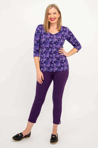 Full body shot of woman modeling Mia Top in violet with matching slim pants, hand on hip