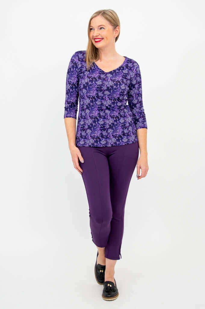 Woman smiling and walking in Mia Top, violet trellis print, and purple cropped pants