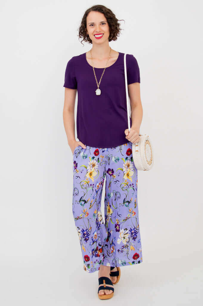 Model styling Landon Capri pants with a purple shirt and accessories