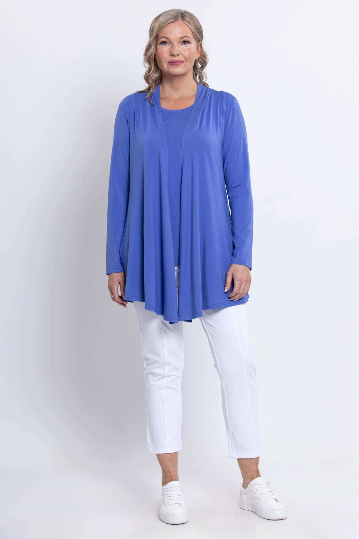 Model standing in Opra long sleeve blue jacket layered over white pants