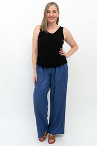 Smiling woman modeling wide-leg blue Tencel denim pants and black sleeveless shirt