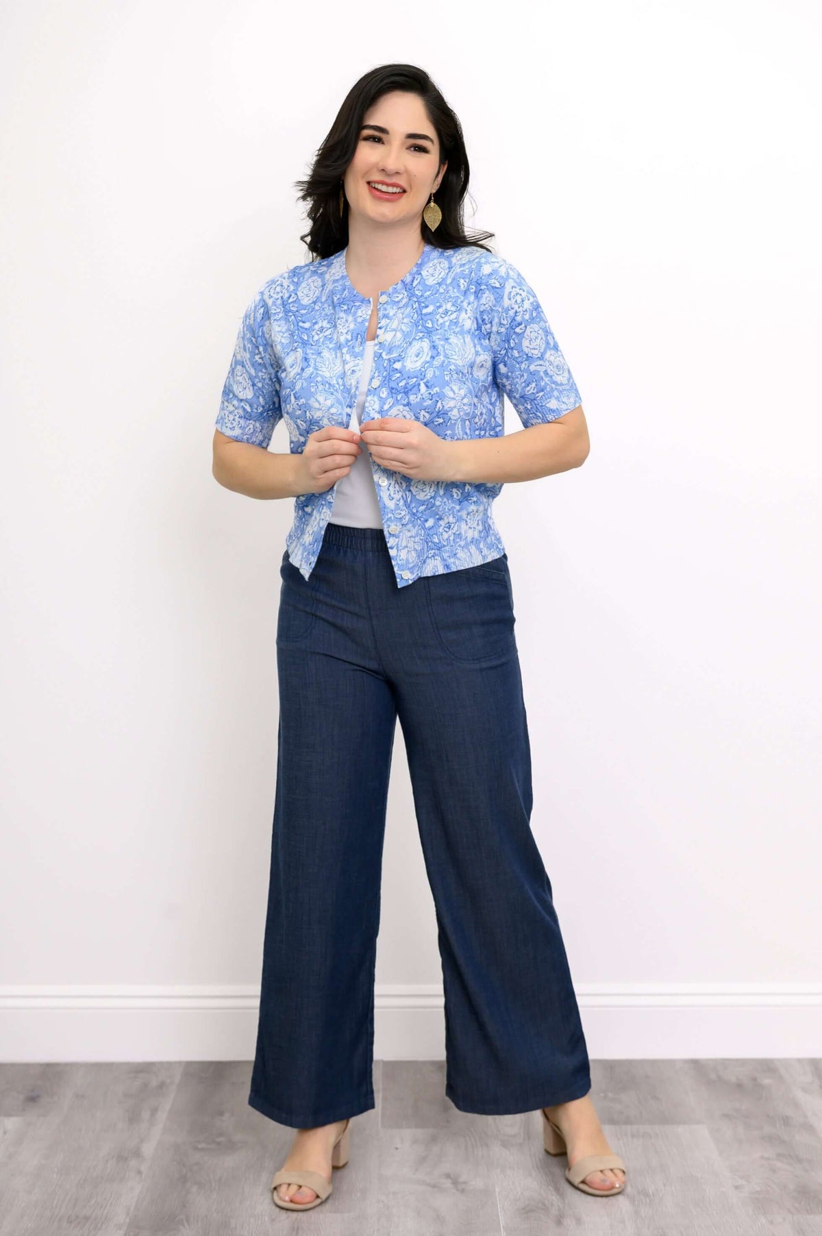 Woman adjusting buttons on blue floral short sleeve cardigan