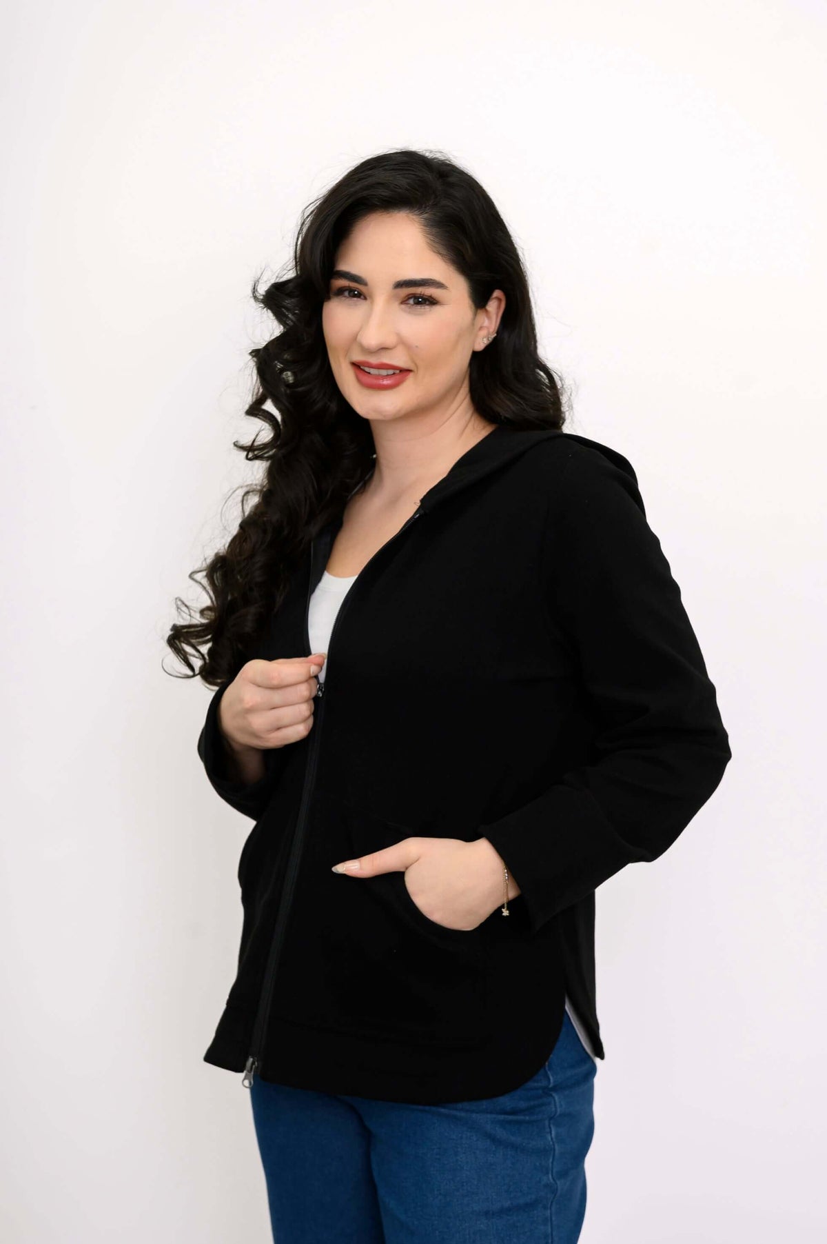Woman adjusting the zipper of a black hoodie with one hand in the pocket