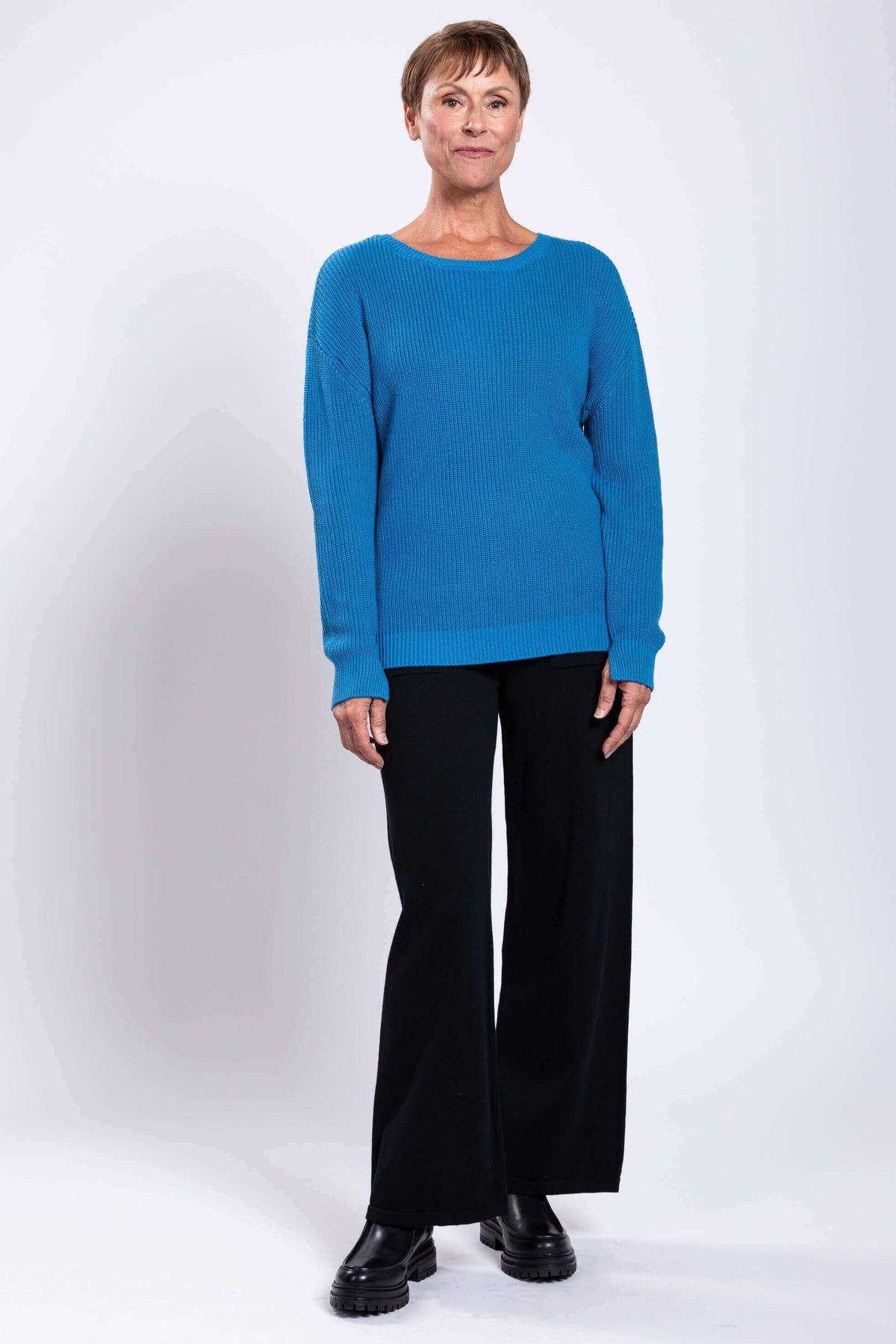 Model showing blue cotton shaker stitch sweater with black pants and boots
