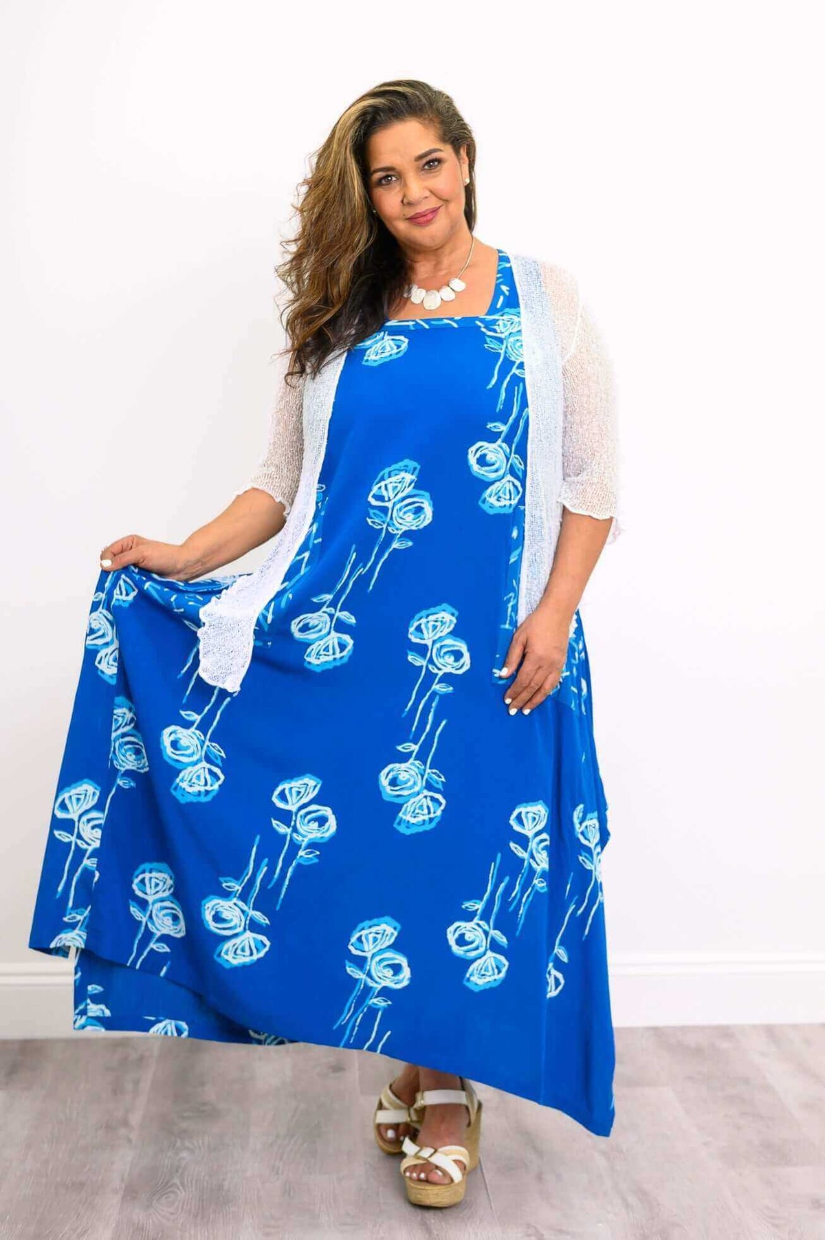 Model holding out skirt of blue floral dress while wearing a soft cardigan