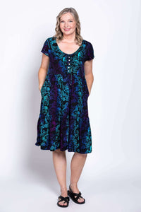 Model showing dress pockets in a black, teal, and purple tiered dress with flutter sleeves
