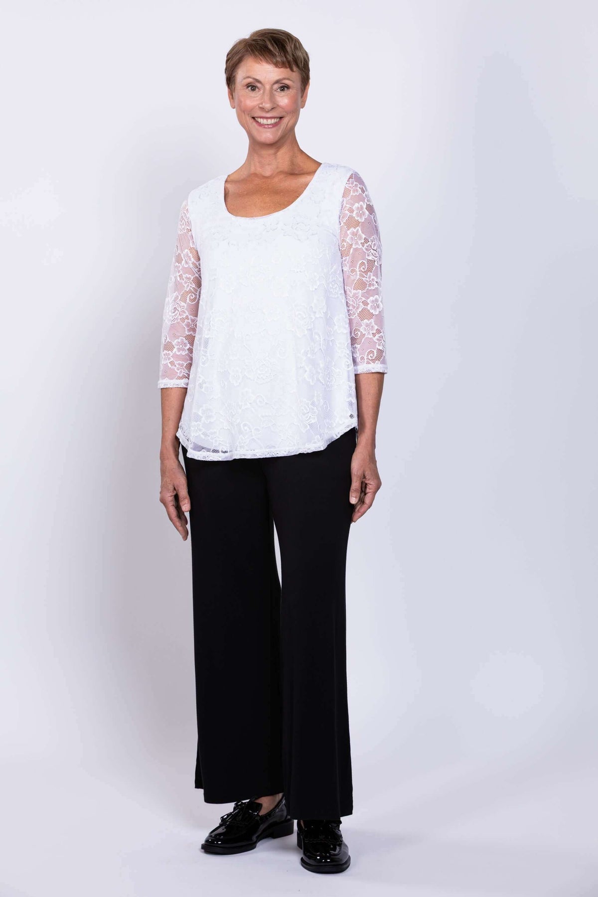 Model standing front-facing in white lace Ellen Top and black pants