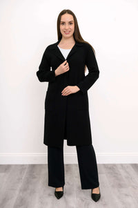 Model standing in black cotton knit jacket, hands on lapel and pocket