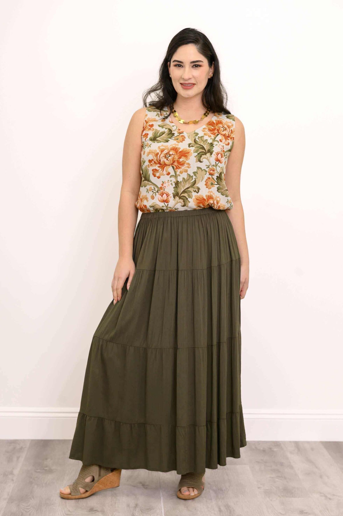 Woman modeling olive green tiered maxi skirt holding skirt hem with one hand