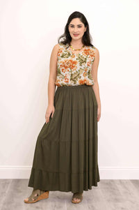 Woman modeling olive green tiered maxi skirt holding skirt hem with one hand