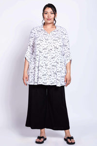 Model in Celine tunic and black loose pants standing against a white background
