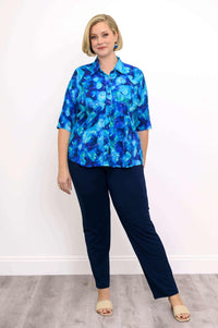 Front view of woman wearing blue patterned button up blouse and dark blue pants