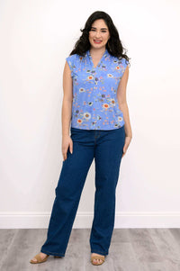 Woman modeling blue floral tank top and jeans in relaxed pose