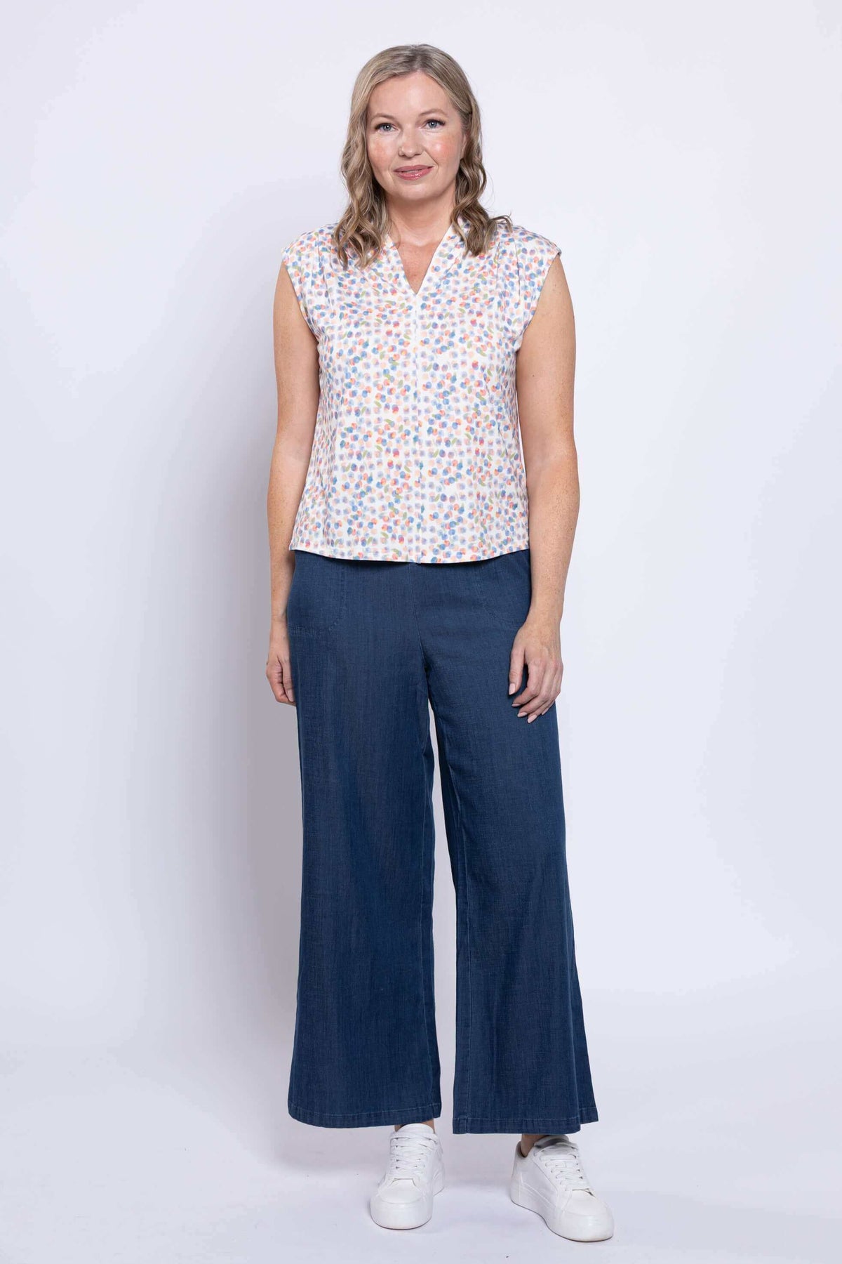 Model standing in Paula Top and wide navy pants with white sneakers