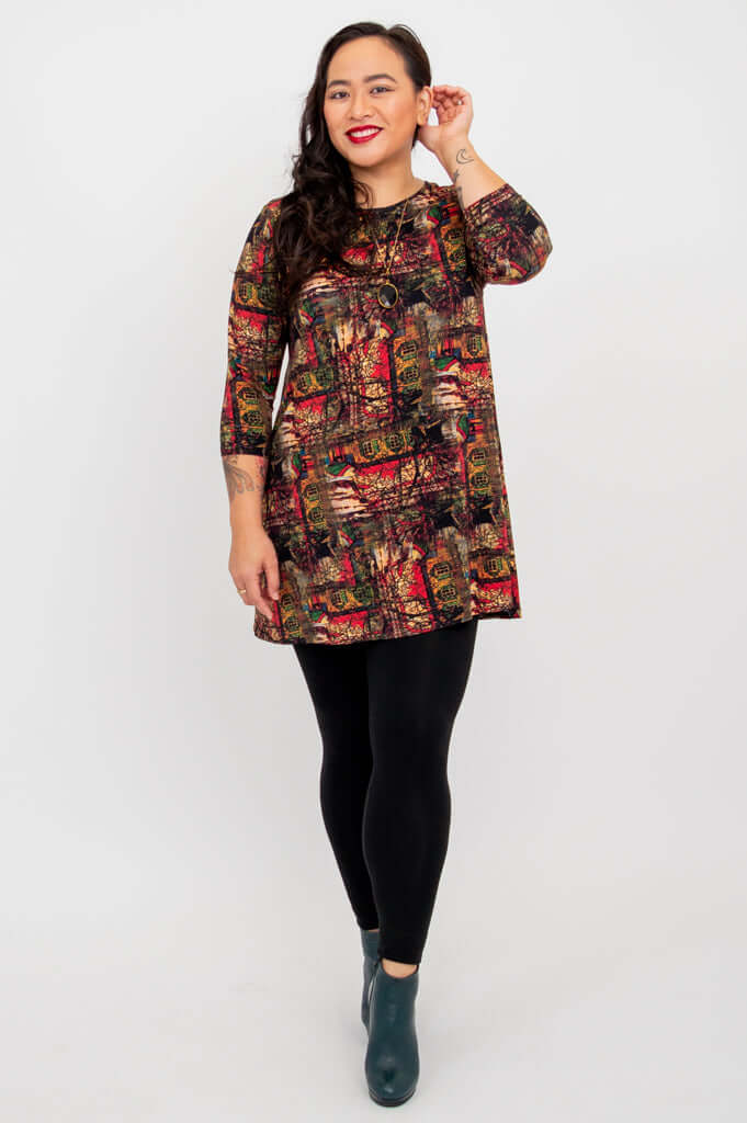 Model posing in Perfect Print A-line tunic with hand raised, wearing black leggings