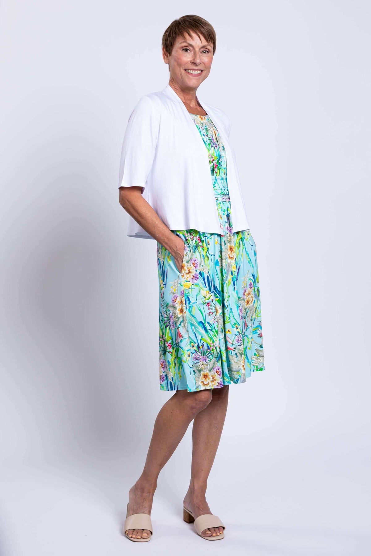 Model in blue floral dress with white cardigan, angled side view