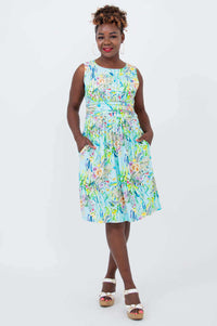 Model wearing sleeveless blue floral dress with ruched bodice and pockets