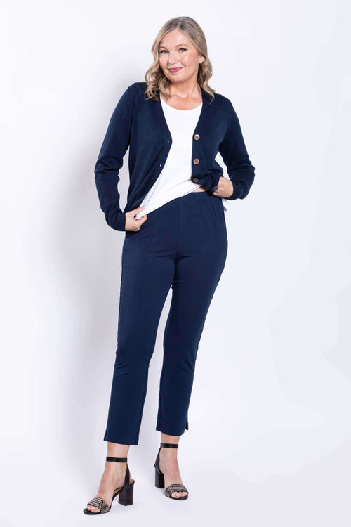 Model wearing navy slim-fit pants with a white top and navy cardigan, front view