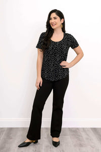 Model smiling in black polka dot Tessa Tee with black pants