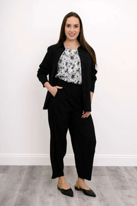 Model styled in black Boardwalk Pants and floral print blouse with hands in pockets