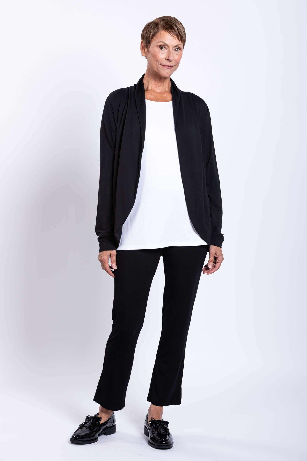 Woman modeling black French Terry jacket, white shirt, and black pants with hands at sides