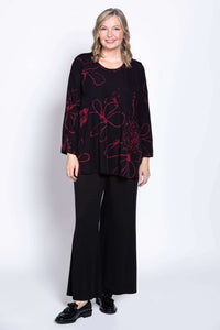 Model in black blouse with berry pattern, facing forward, wide-leg pants visible