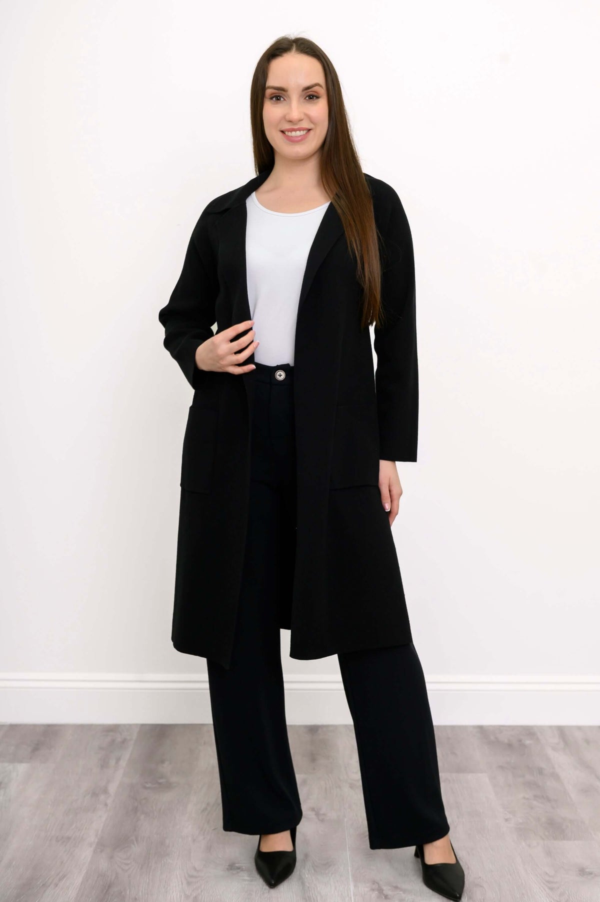 Model posing in black cotton knit open front jacket with two pockets