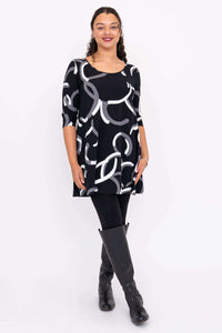 Model posing in black dress with white and gray curved print, paired with knee-high boots