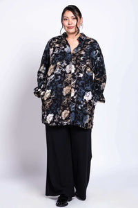 Model in black floral batik shirt, hands in pockets, posing frontally