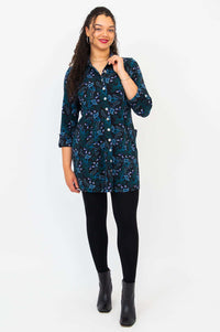Model standing in black patterned button-down tunic shirt with hands in pockets