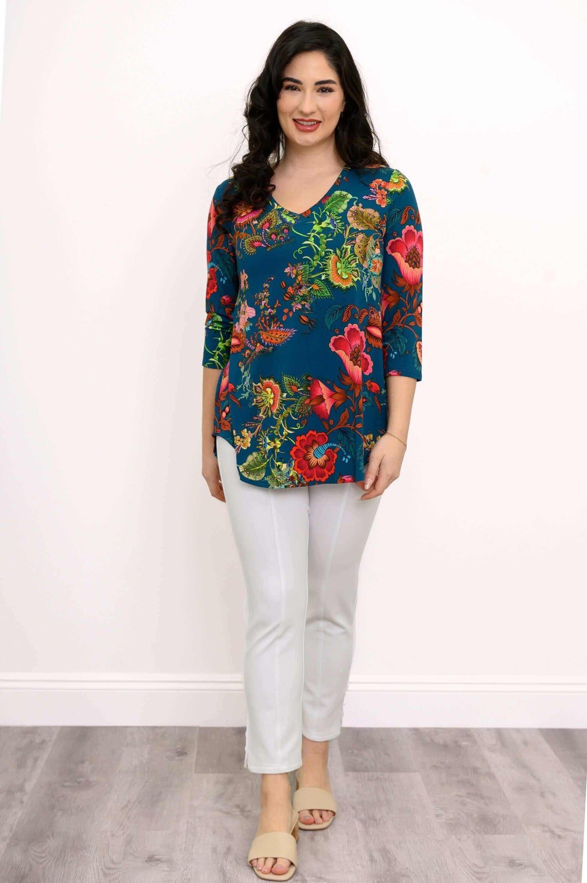 Woman modeling a blue floral V-neck top with white pants and sandals