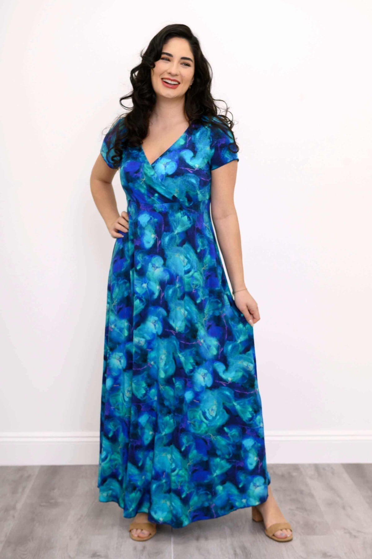 Model in blue floral bamboo maxi dress smiling and holding skirt