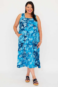 Model standing in blue floral square neck dress, hands in pockets, front view