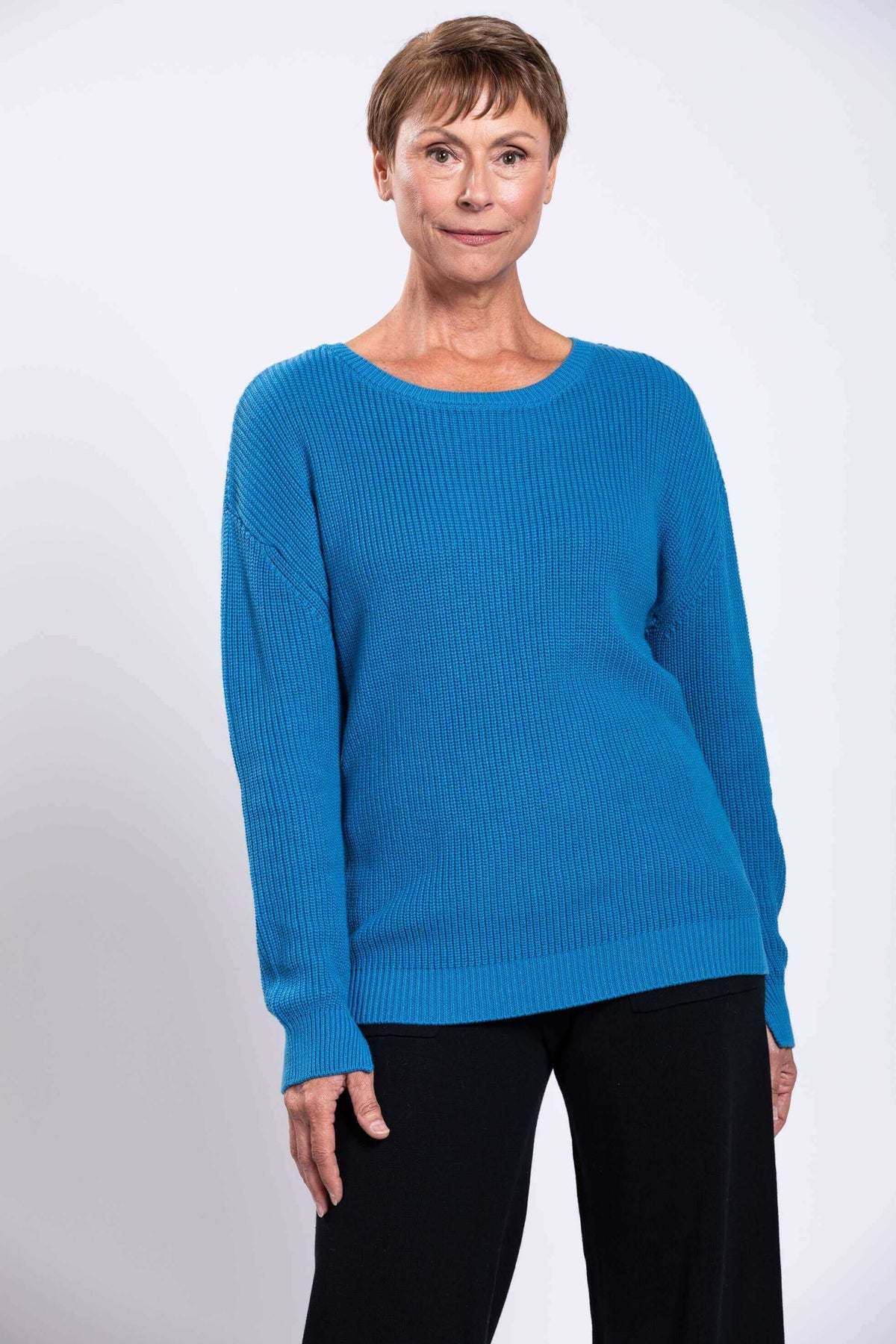 Model wearing a blue shaker stitch sweater with relaxed long sleeves