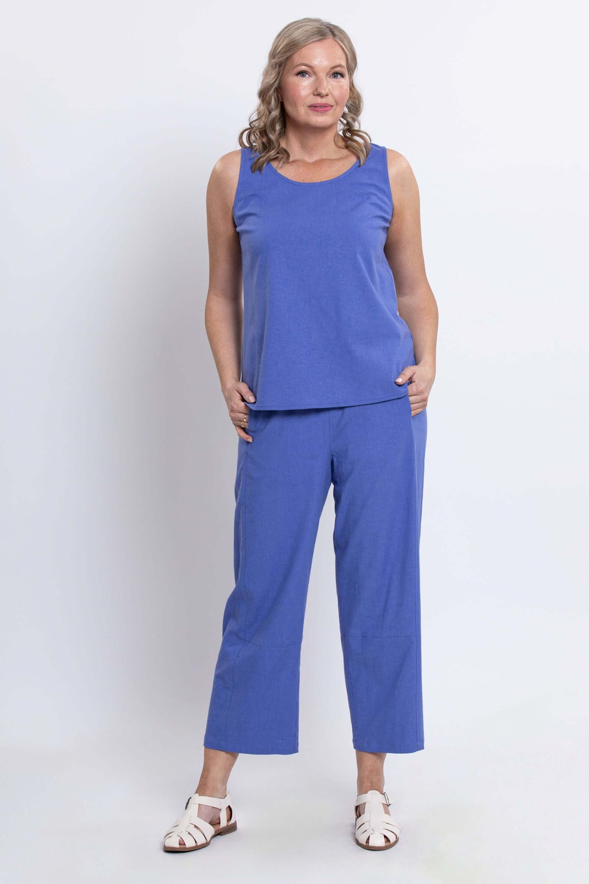 Model wearing blue sleeveless top and cropped Boardwalk pants, front view with hands in pockets