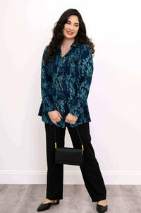 Model in blue smocked tunic holding a black handbag, smiling