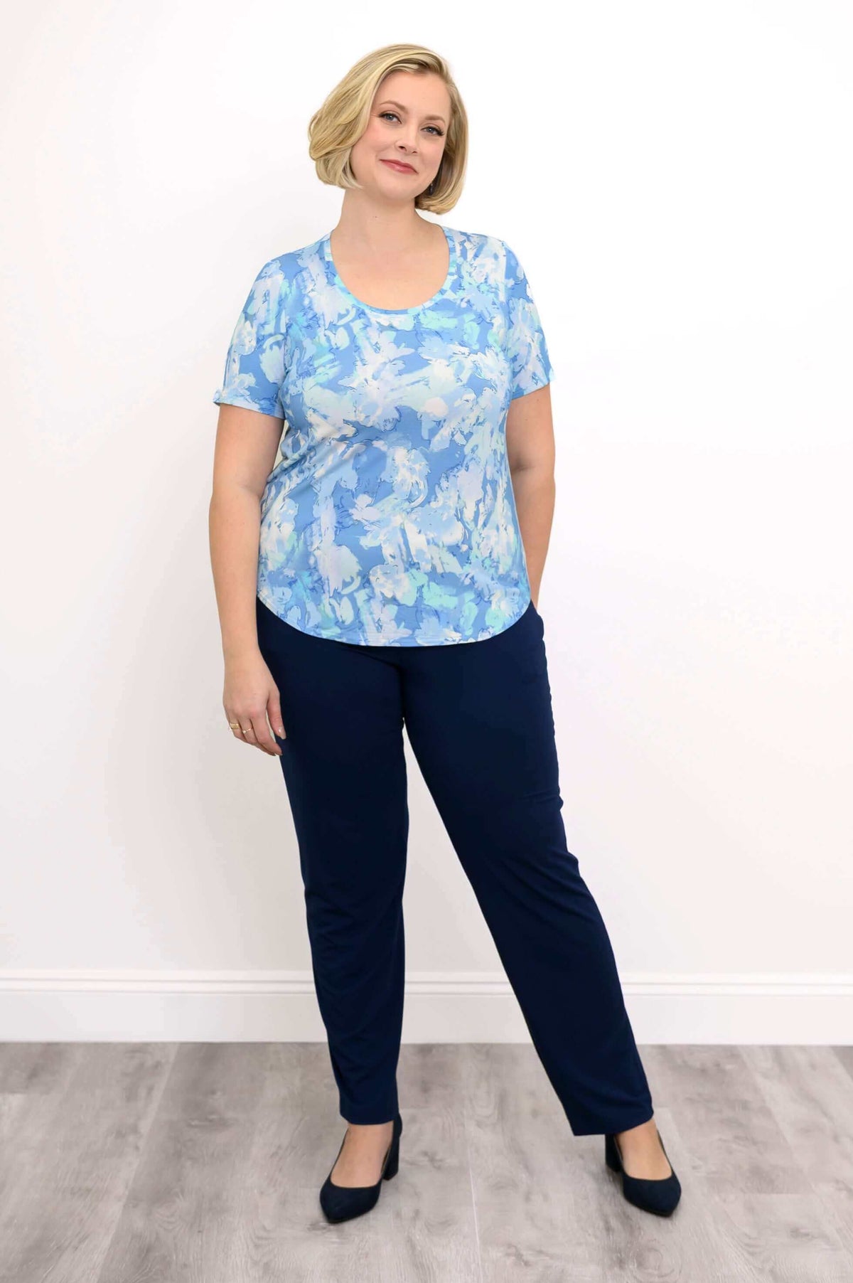 Woman modeling a blue watercolor scoop neck tee and navy pants with hands in pockets