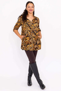 Full-length front view of a woman in botanical print Celine Oversized Tunic, brown leggings and black boots