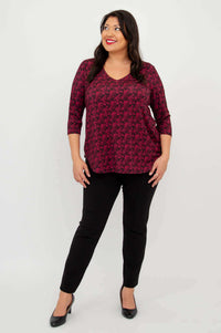 Model posing in coral print V-neck bamboo top with black pants and heels