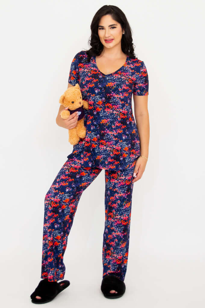 Model wearing matching floral bamboo lounge top and pants while holding a teddy bear