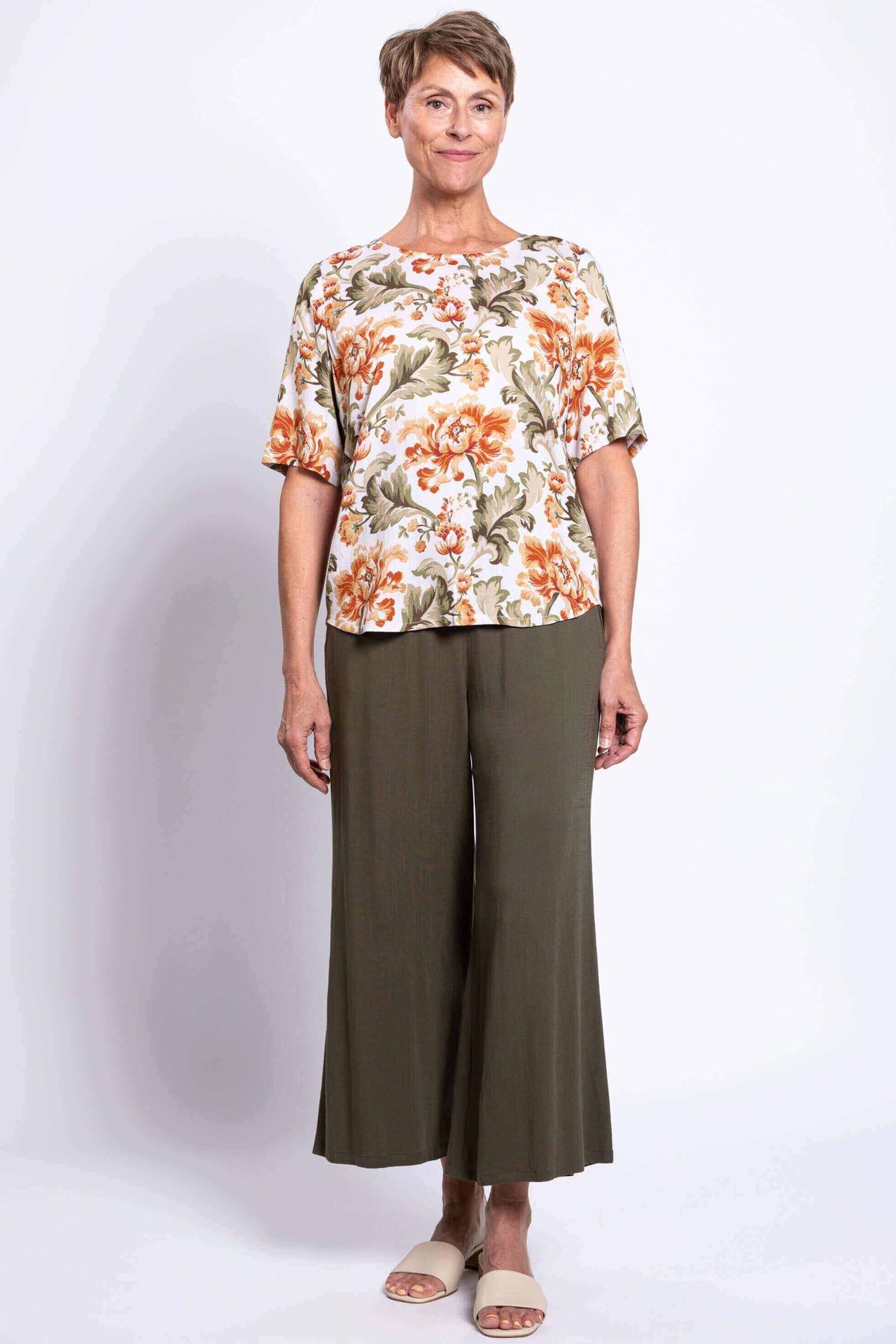 Woman modeling floral blouse with elbow sleeves and olive pants, front full body view