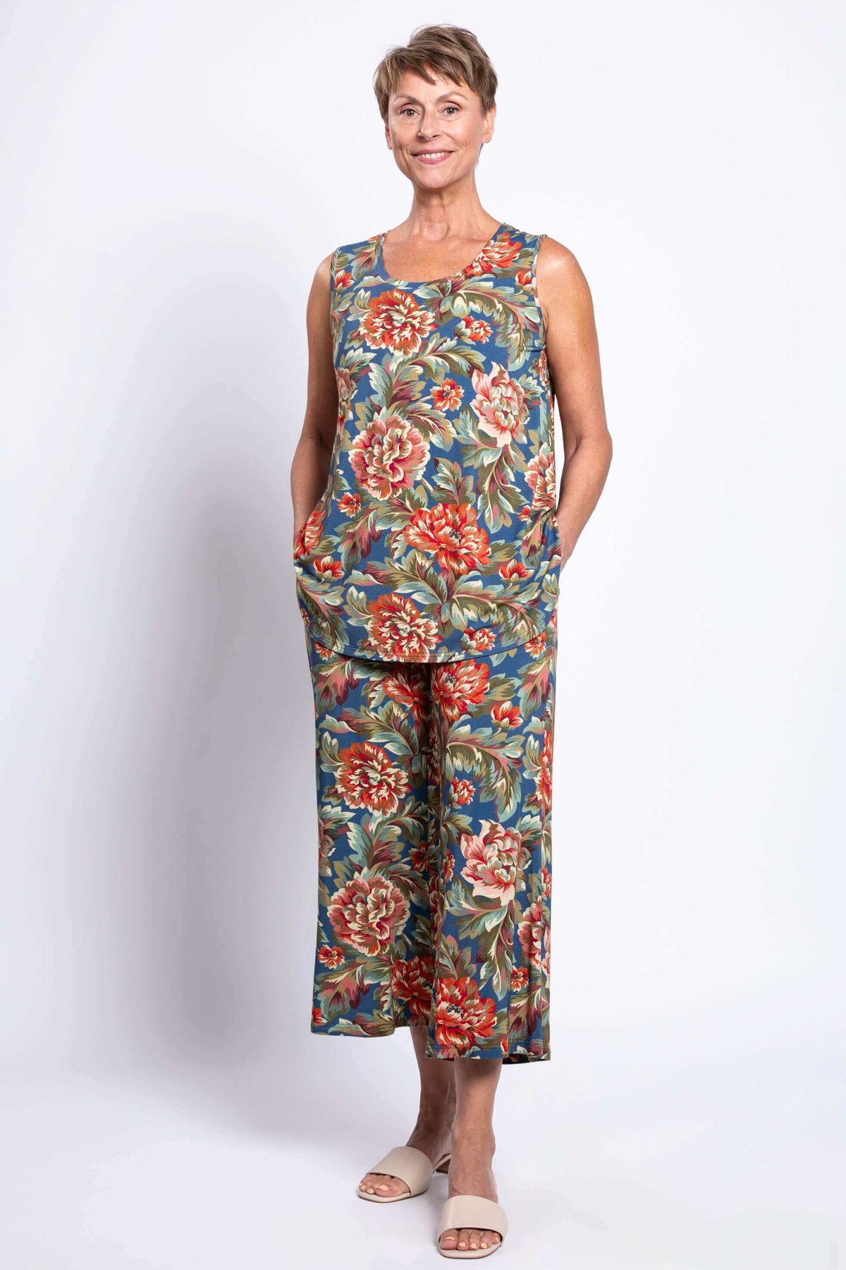 Smiling model in matching floral tank and wide leg pants, hands in pockets