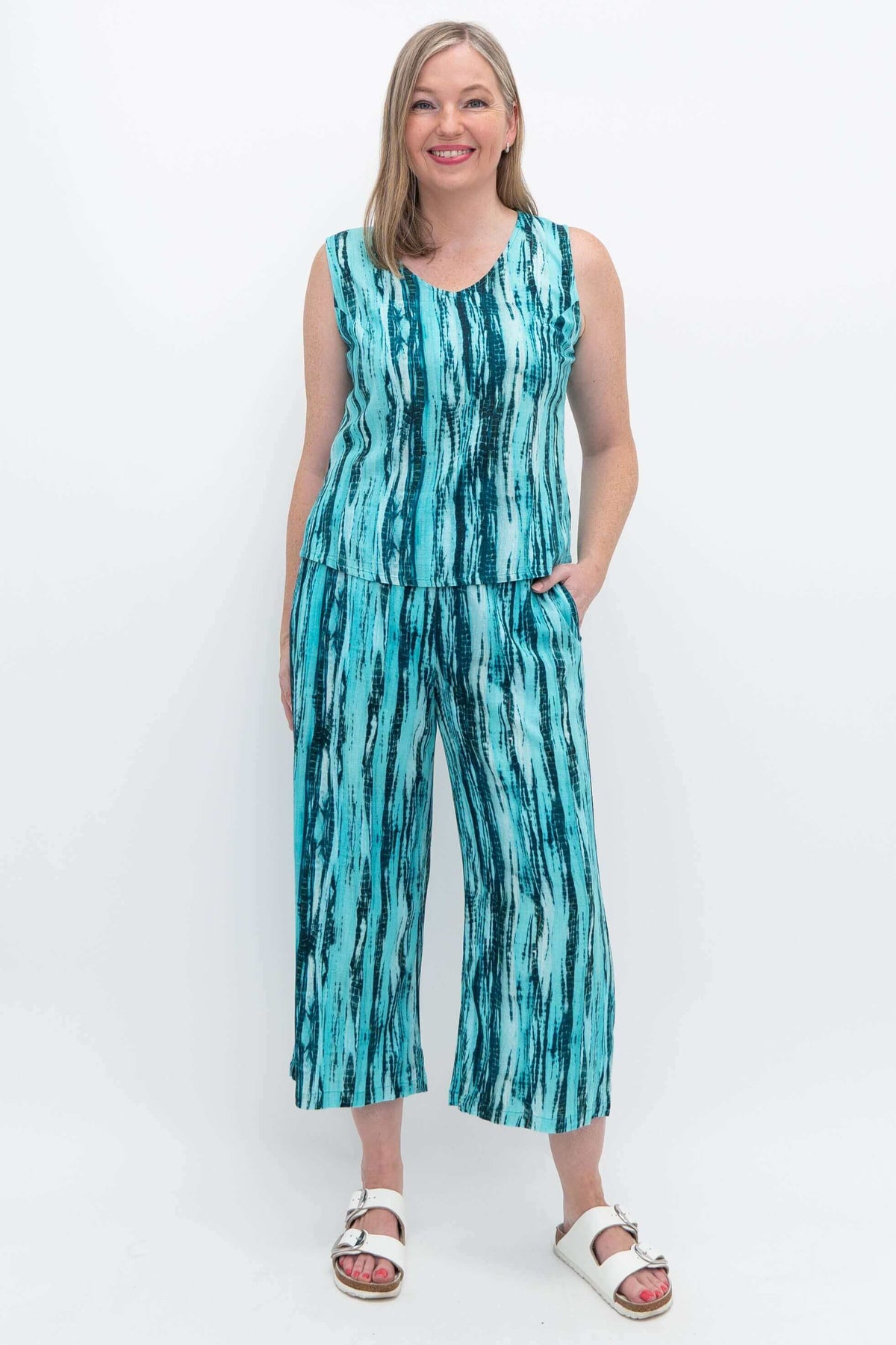 Woman wearing matching teal bamboo linen tank and Landon Capri pants, hands in pockets