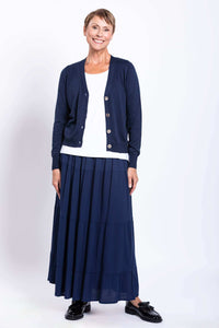 Full front view of model smiling in dark blue cardigan and matching skirt paired with a white top
