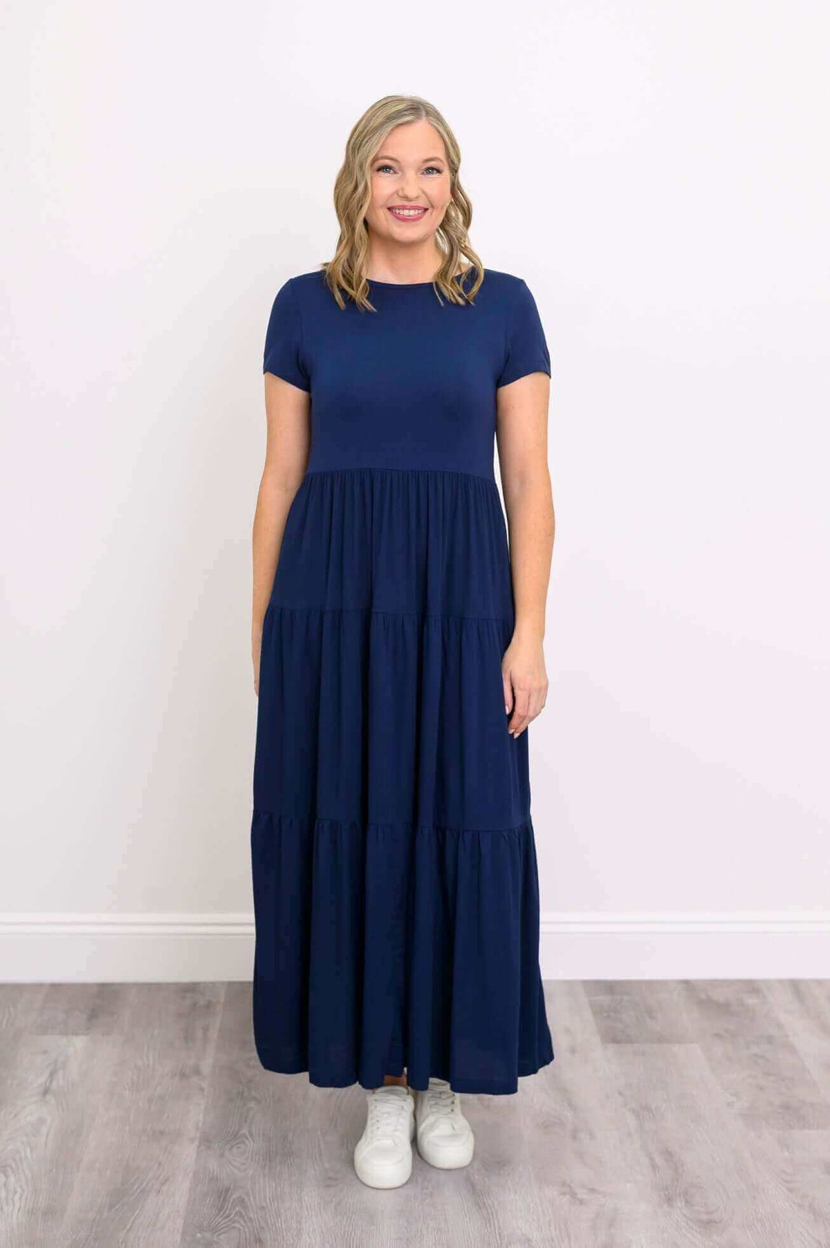 Model in navy tiered maxi dress smiling and standing straight