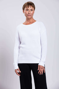 Model posing in a relaxed white cotton sweater with ribbed hem and cuffs